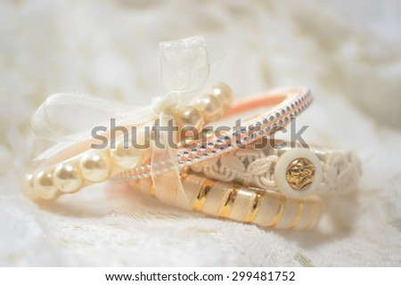 Soft Focus of Sweet Pastel Peach Beads and Peals Bracelet with Ribbons, Isolated on Cream Lace Cloth Fabric [Vivid Bright Collection]