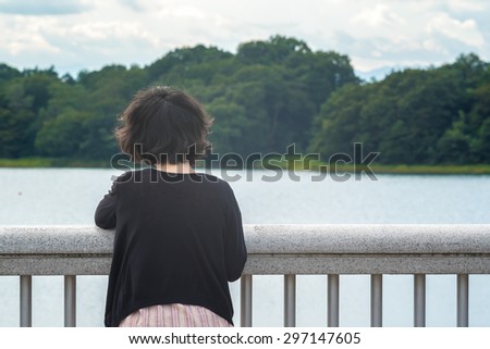 Asian woman looking at sky and lake