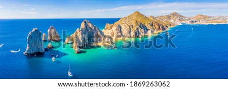 Aerial panoramic view of Lands End and El Arco at the tip of Baja California Sur, with the Cabo San Lucas, Mexico marina in the background