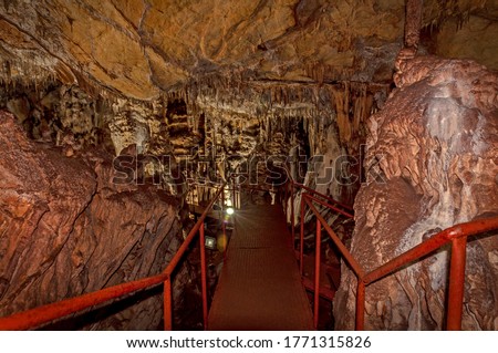 Little known cave Dobrostanski biser - Bulgaria. Illuminated and ennobled cave with a red metal ladder and a path for fasting Imagine de stoc © 