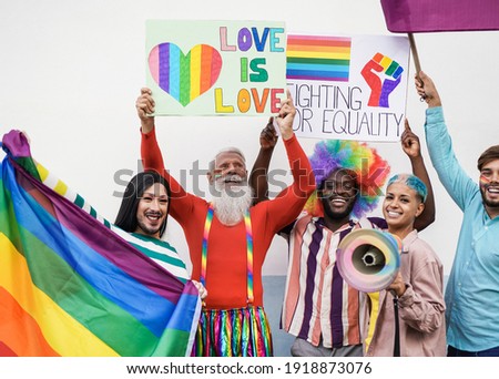 Multiracial homosexual people having fun at lgbt pride parade outdoor with banner and rainbow flag