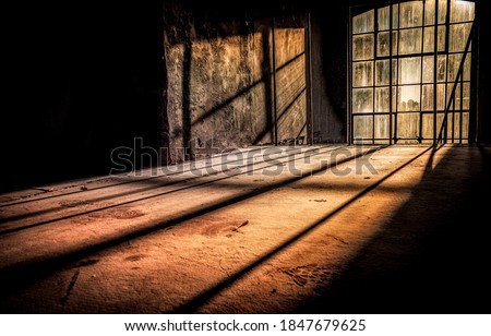 Sun rays fall through tall windows into an abandoned dusty room. Sunlight window in darkness. Dark sunlight window. Tall window sunlight