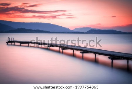 Sunset over the mountain lake pier. Sunset lake pier. Lake pier at sunset. Mountain lake pier at sunset
