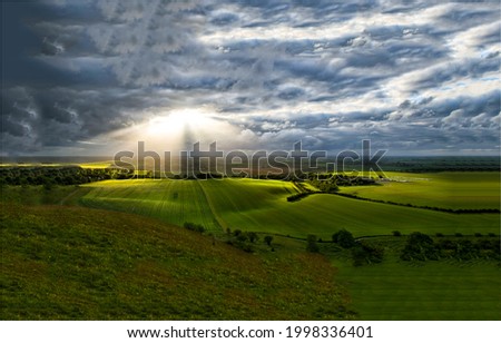 The sunrays break through the storm clouds. Agriculture field above stormy sky clouds. Storm clouds before rain. Agriculture rainy weather