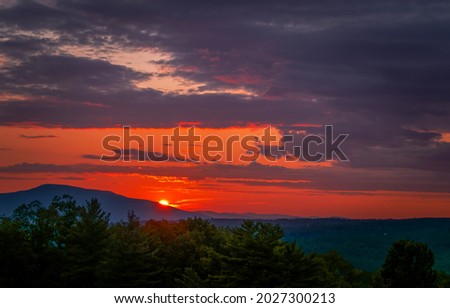 Sunset over a mountain peak. Mountain sunset peak. Red sunset landscape. Beautiful sunset sky clouds landscape