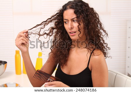 woman looks at her broken hair