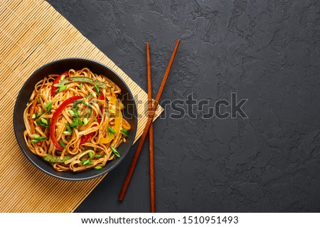 Vegetarian Schezwan Noodles or Vegetable Hakka Noodles or Chow Mein in black bowl at dark background. Indo-chinese cuisine hot dish with udon noodles, vegetables and chilli sauce. Copy space Foto d'archivio © 