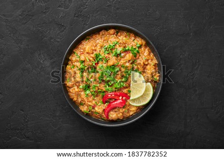Baingan Bharta or Roasted Mashed Eggplant in black bowl on dark slate table top. Bhurta is indian cuisine puree dish of fire roasted eggplant and masala. Top view