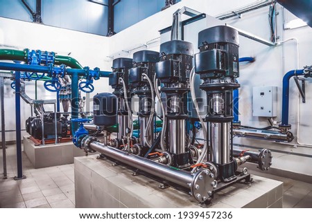 Industrial interior of water pump, valves, pressure gauges, motors inside engine room. Valve and pumps in an industrial room. Urban modern powerful pipelines and pumps, automatic control systems