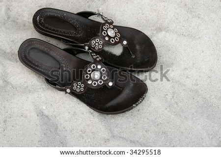 Pair of brown shoes with silver pattern design on the sand