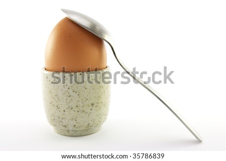 Lightly boiled egg in an egg cup with a spoon on a white background