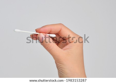 Closeup of female hand holding cotton stick isolated on white background. Dna test. Cotton swab. Close up of woman's hand holding a cotton bud. Studio shot isolated on white. White cotton buds. 