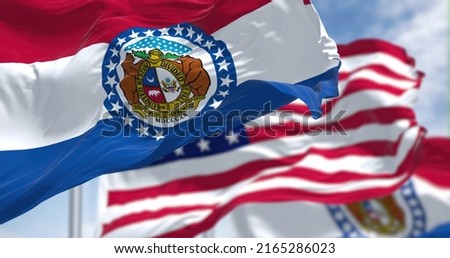 The Missouri state flag waving along with the national flag of the United States of America. In the background there is a clear sky. Missouri is a state in the Midwestern region of the United States 商業照片 © 