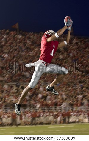African American football wide receiver leaping up to catch a football. Vertically framed shot.