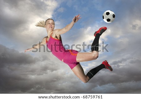Female soccer player kicking a ball in midair.
