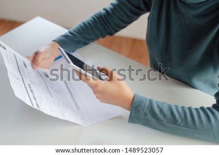 hands of young woman using mobile smart phone for scan and payment online with family budget cost bills on desk in home office, plan money cost saving, investment, business finance, expenses concept