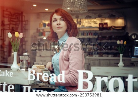 beautiful young woman is having tee and cake in a nice cafe. Photos in purple tones