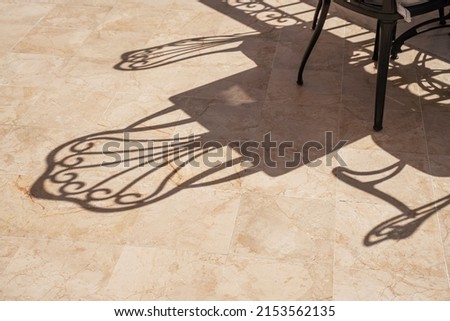 Photo of Shadows from empty chairs in a cafe under the hot sun.