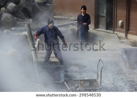 Hakone, Japan - April 9, 2015: Unidentified man is boiling black eggs believed to help extend 7 years of life if eating one at Owakudani, a volcanic valley with active sulphur vents and hot springs.