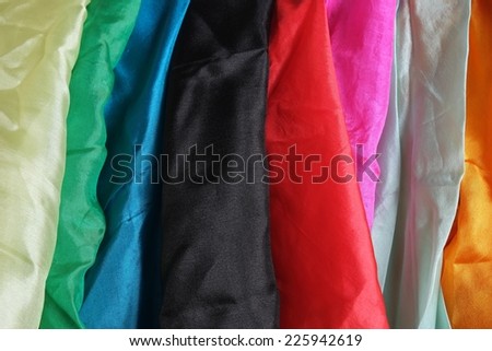 A colorful mixture of several shiny silk handkerchiefs hanging down. Red, blue, aqua blue, black, yellow, orange, pink, fuchsia, golden, green, gray, silver. Magic theme