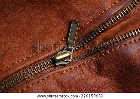 Sleeve zipper detail of a brown leather jacket, showing nylon seams
