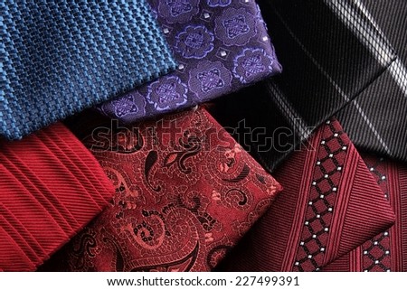Rolled up modern and classic silk ties on top of each other. Blue, red, purple, bordeaux and black