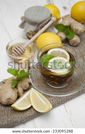 A cup of tea with fresh honey, lemon, ginge on wooden background