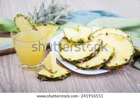 Glass of pineapple juice with fresh fruits on a wooden background