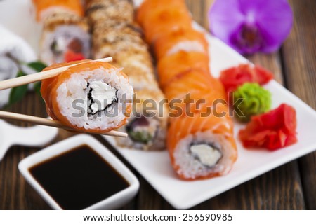 Different Sushi rolls,wasabi and ginger on a plate on wooden background