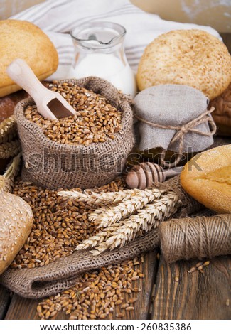Different bread with wheat in a small bag,honey and milk on a wooden background