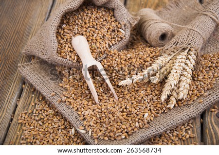 Wheat grain in a small bag on wooden background