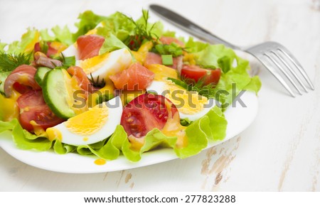 Mixed salad with slices of salmon and honey - mustard sauce on a wooden background
