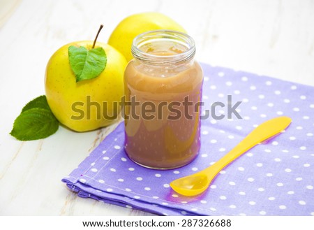 Baby apple puree in a jar with apples on wooden white background