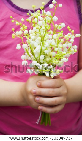 Bouquet of lilies of the valley in the hands of a little girl
