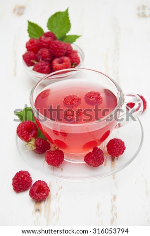 A cup of tea raspberry with fresh raspberry on a white wooden background
