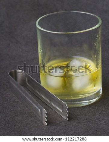 Whisky with ice over a black background, with an ice pick