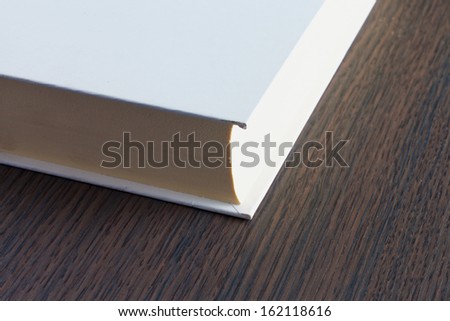 White covered book over a wooden table in closeup