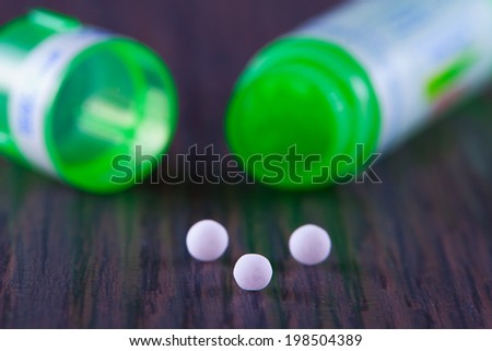 White granules of homeopathic medicine, over wooden table