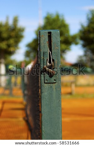 Close up of the side of a tennis net on a clay court