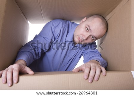 man in blue shirt looking out of cardboard box