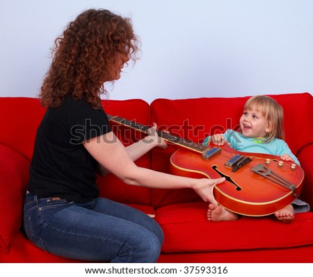 little girl and woman play with electric guitar