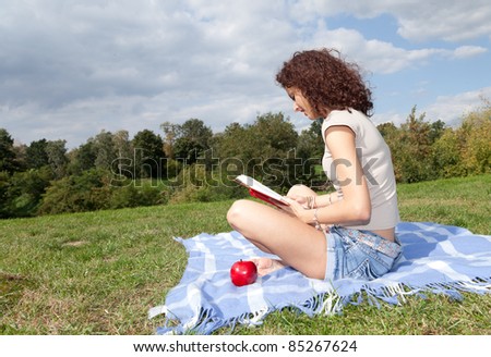 young woman reading or studying book outdoors at summer camp
