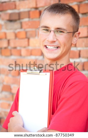 teenage male student with blank clipboard, outdoors