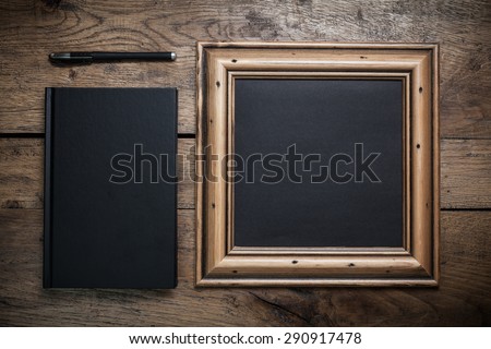 Black leaf framed diary notebook and pen on vintage wooden desk