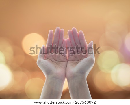 Empty female open human hands with palms up among candle lights bokeh  in natural warm gold color tone background: Pray for spiritual support and helping concept: Night of power, novel, destiny