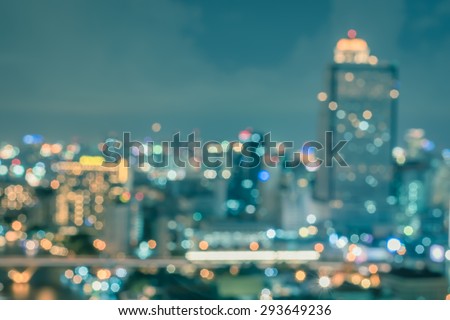 Blurred abstract background aerial view of Bangkok downtown city night lights with colorful bokeh in cool vintage cyan turquoise blue tone: Central business district on electric train line over river