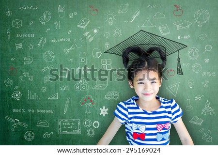 Happy Asian school child girl with heart shaped hair on green color chalkboard background with freehand daydreaming doodle: Smiling female little kid on writable cement concrete backdrop with drawing