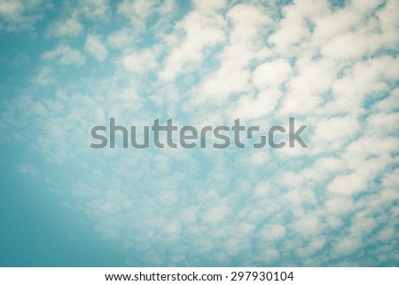 Vintage style paper texture with blurred nature background of blue sky and soft scattered clouds from the corner: Water colour textured paper with blurry retro sky