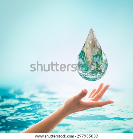 Human hand reaching the green water globe droplet with clear turquoise blue background: Save water, earth and environment protection/ campaign concept: Elements of this image furnished by NASA