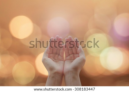 Empty female open human hands with palms up on blurred abstract background of candle lights bokeh in natural warm gold color tone: Destiny and pray for peace concept: Humanitarian aid